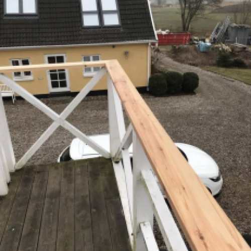 Tømrer udfører tømrerarbejde med montering af altan og gelænder i træ i Vestsjælland