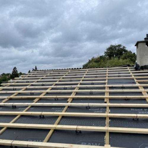 Tømrer udfører tømrerarbejde med tagrenovering og montering af undertag og lægter