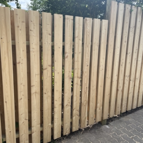 Tømrer udfører tømrerarbejde med montering af træhegn i haven