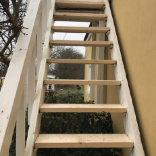 Tømrer udfører tømrerarbejde med opbygning af udvendig trappe i træ