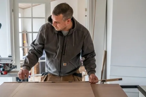 Erfaren tømrer i Vestsjælland måler og tilpasser materialer til professionelt tømrerarbejde