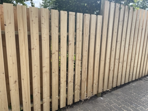 Tømrer udfører tømrerarbejde med montering af træhegn i haven