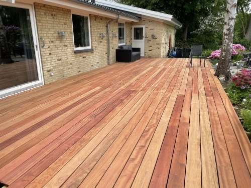 Tømrer udfører tømrerarbejde med stor træterrasse ved enfamiliehus