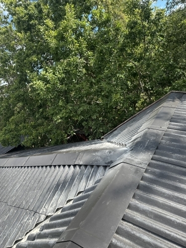 Tømrer udfører tømrerarbejde med taginddækning og afslutning ved tagryg