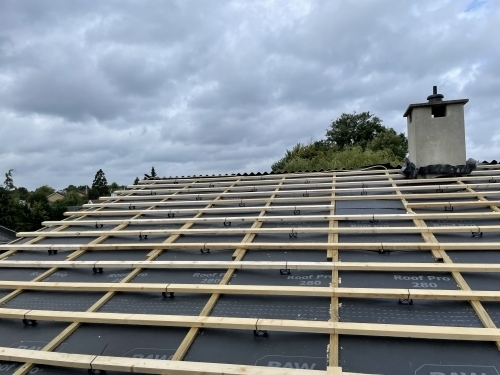 Tømrer udfører tømrerarbejde med tagrenovering og montering af undertag og lægter