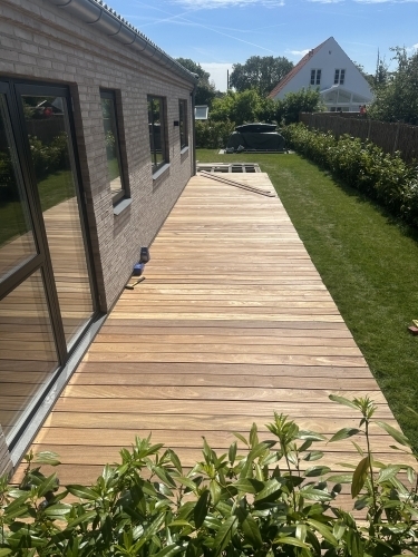 Tømrer udfører tømrerarbejde med opbygning af træterrasse langs bolig i Vestsjælland